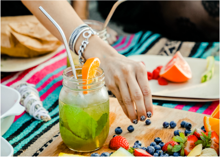 A person is holding their hand over a glass of lemonade.