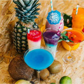 A table topped with glasses of blue curacao and pineapple.