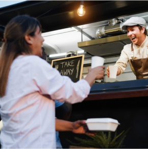 A woman is handing out food to a man.