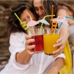 Two women holding drinks with straws in them.
